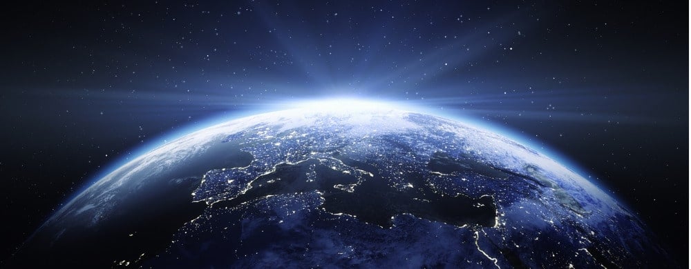 Earth at night with city lights visible across continents against a starry sky.