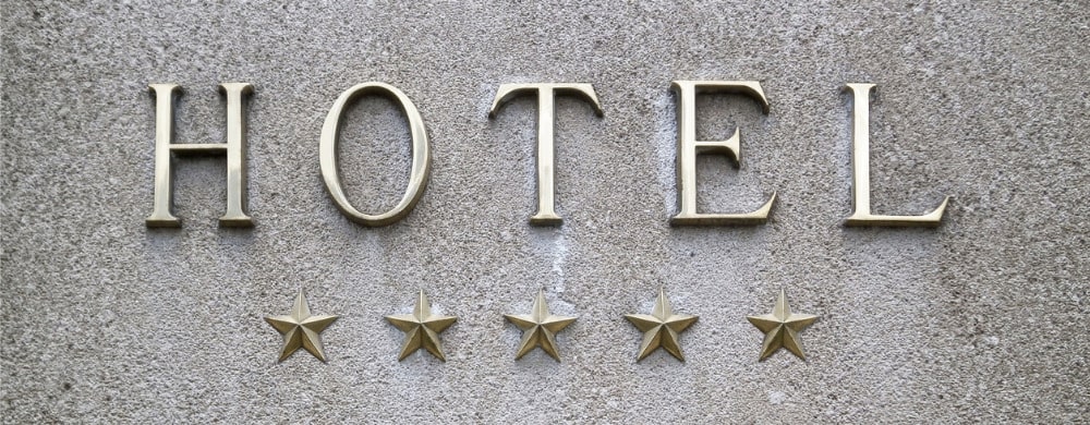 The word "HOTEL" in raised letters above five gold stars on a concrete surface.