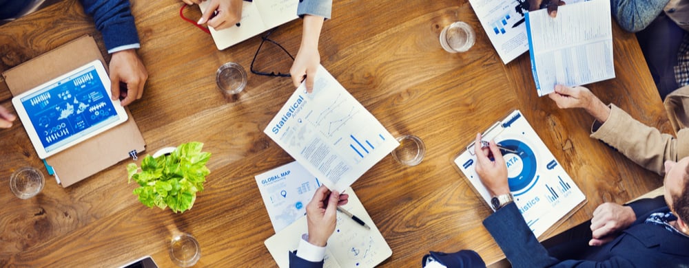 Business team reviewing analytics reports and charts at a wooden table.